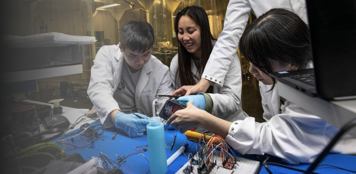 Students work together on a piece of electronic equipment